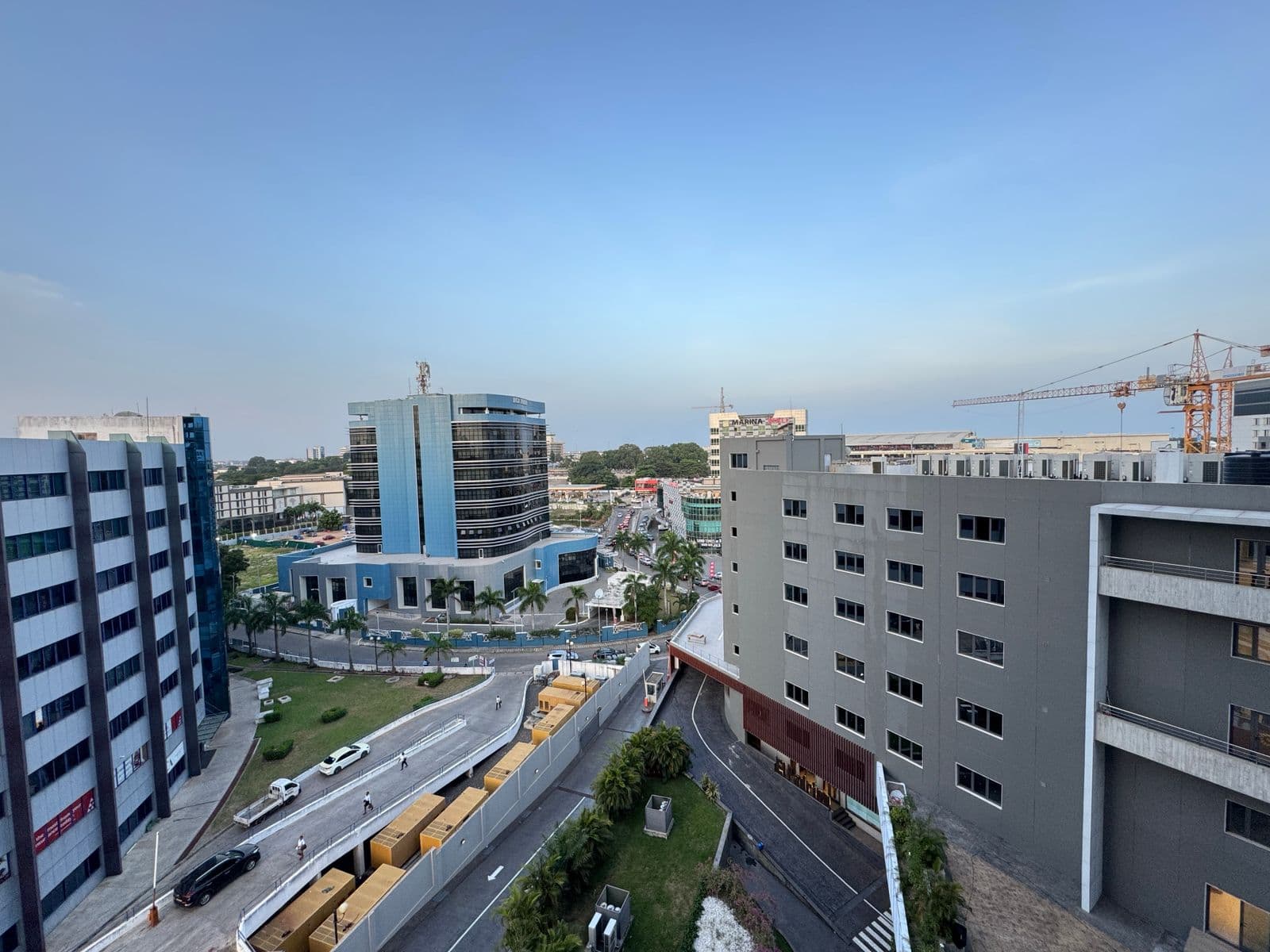 Modern Accra cityscape with office buildings, palm-lined streets and a construction crane — DXtrend Global's home city.