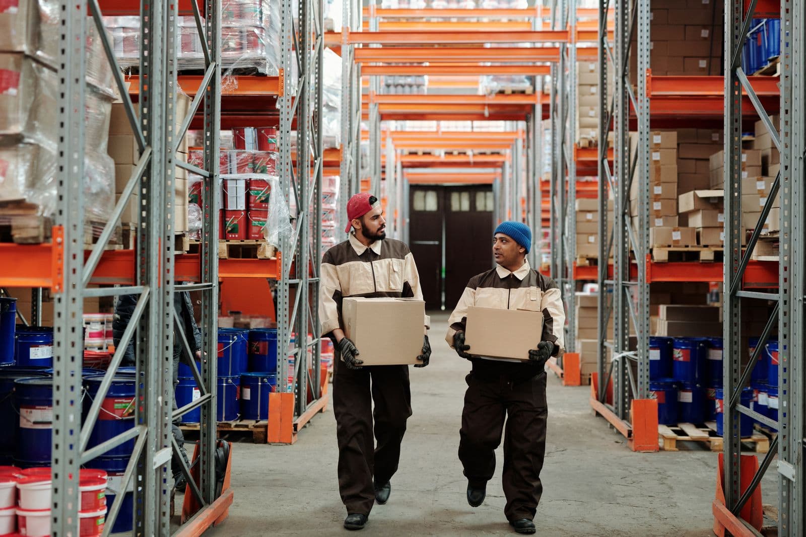 Warehouse workers moving boxed goods along a racking aisle for distribution.