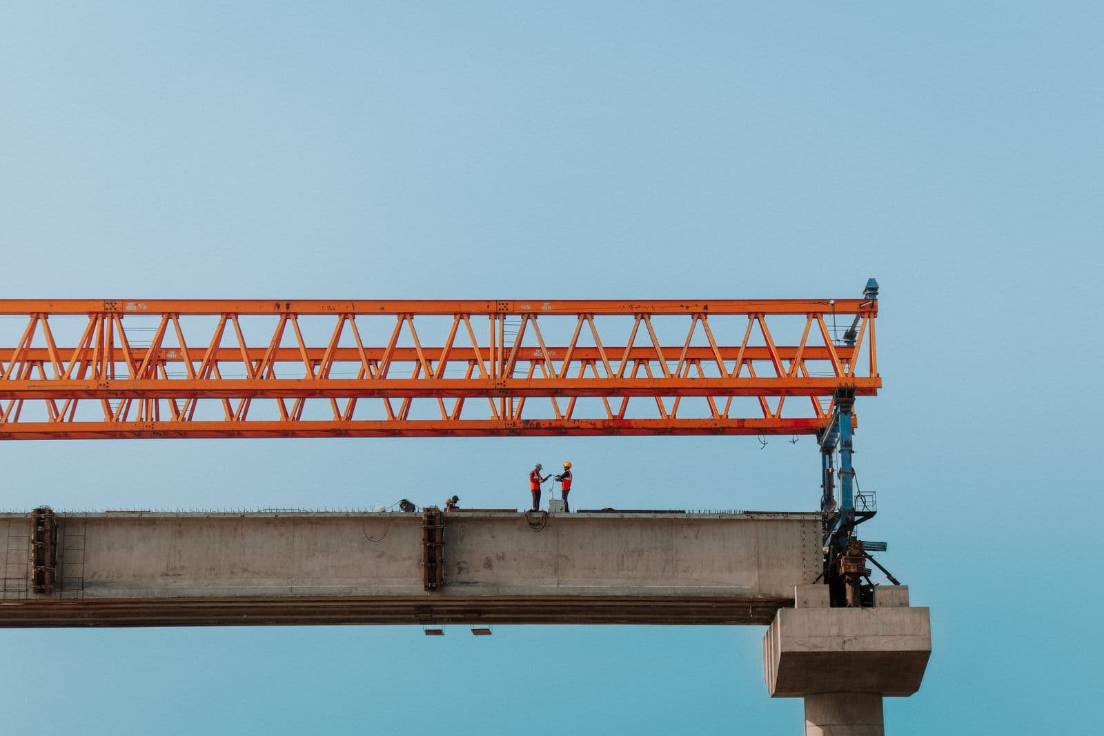 Civil-works construction with a launching gantry and site workers in high-visibility gear.