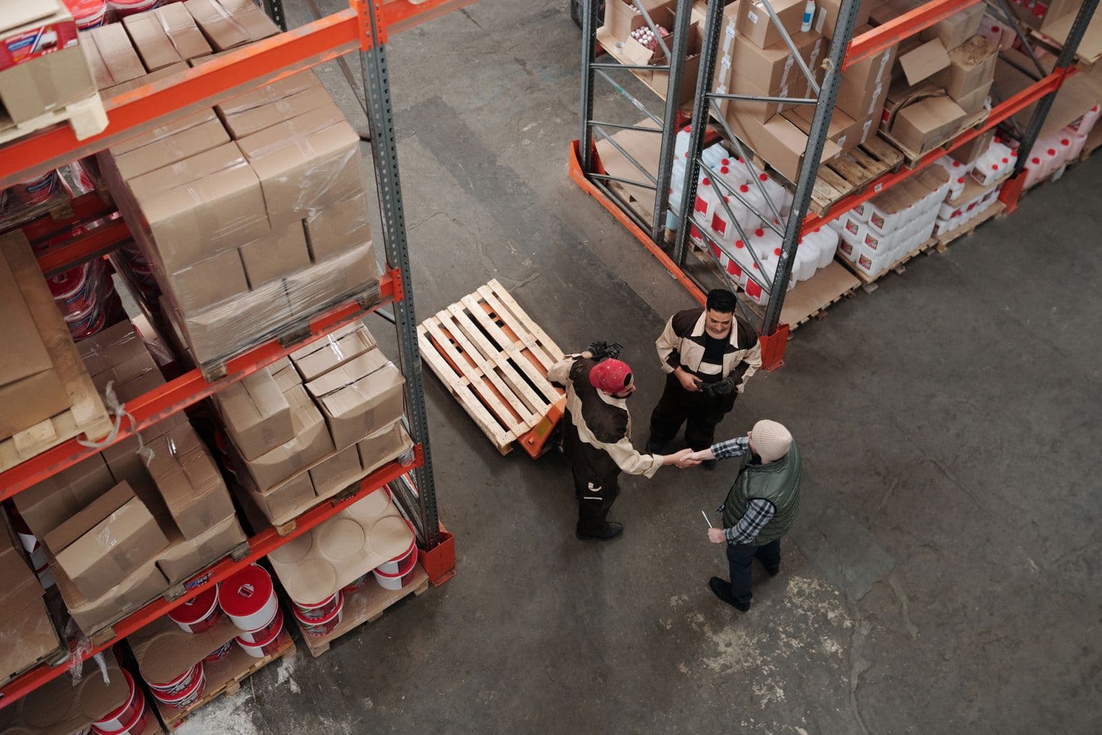 Warehouse team handling stored goods on racking — sourcing and supply operations.